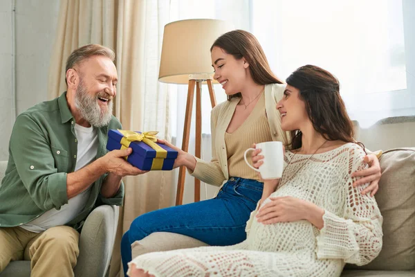 Молода весела жінка тримає дивовижний подарунок від батька свого щасливого вагітного партнера, концепція IVf — стокове фото