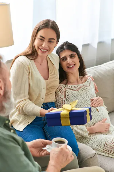 Mujer embarazada feliz abrazo con su pareja con regalo en las manos mirando a su padre, concepto ivf - foto de stock