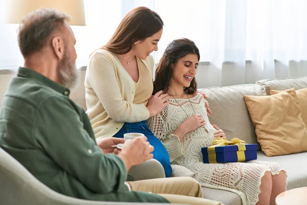 Father drinking coffee looking at his daughter and her partner, hand on pregnant belly, ivf concept — Stock Photo