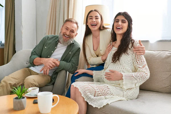 Father with his daughter and her partner on sofa looking at camera, in vitro fertilization concept — Stock Photo