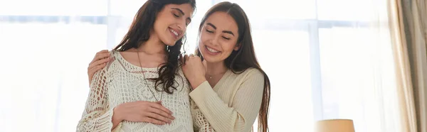 Happy lgbt couple hugging warmly with hand on pregnant belly with closed eyes, ivf concept, banner — Stock Photo