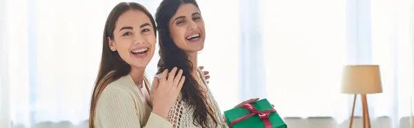 Freudiges lesbisches Paar mit Geschenk in den Händen, fröhlich lächelnd in die Kamera, ivf concept, Banner — Stockfoto