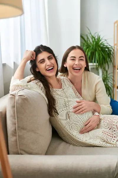Cheerful lgbt couple relaxing on sofa and smiling happily at camera, in vitro fertilisation concept — Stock Photo