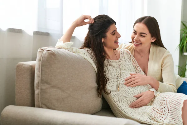 Jolly expecting couple sitting on sofa smiling warmly at each other, in vitro fertilisation concept — Stock Photo