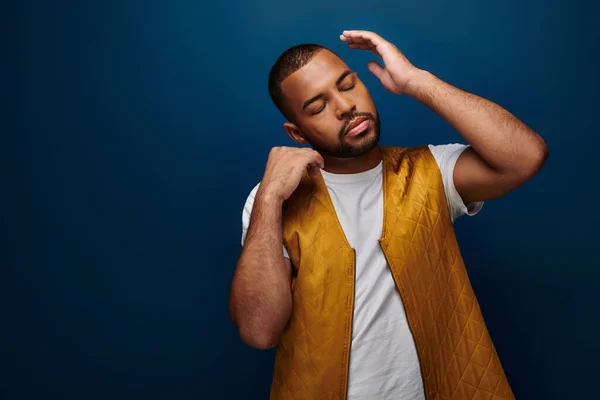 Élégant jeune homme en gilet jaune tendance posant avec les yeux fermés et les mains près du visage, concept de mode — Photo de stock