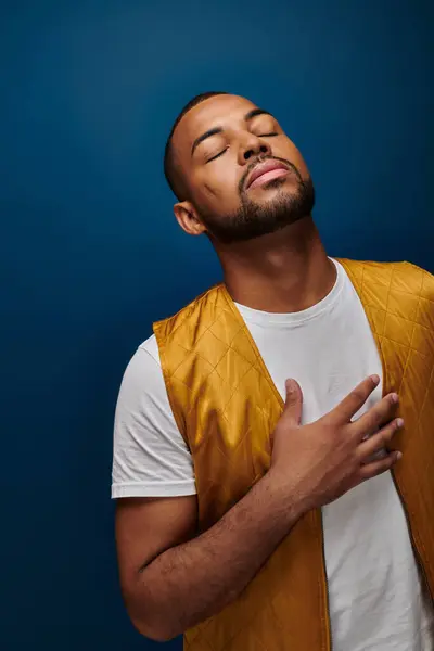 Handsome african american man in yellow jacket posing with hand on his chest, fashion concept — Stock Photo