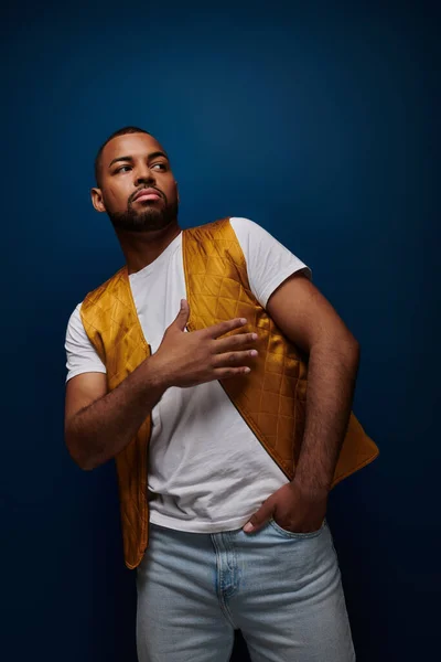 Jeune homme afro-américain posant avec une main dans la poche et une sur sa poitrine, concept de mode — Photo de stock