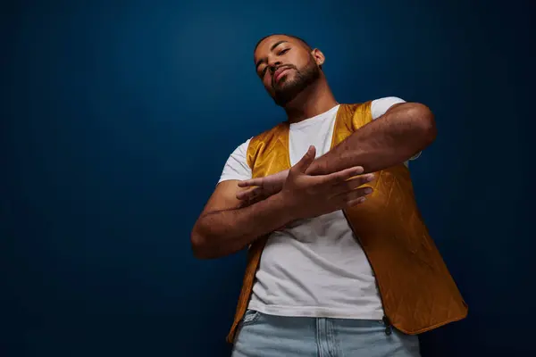 Beau jeune homme en gilet et jeans croisant légèrement ses bras la paume de la paume à la paume, concept de mode — Photo de stock