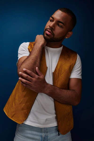 Jeune homme beau en gilet jaune à la mode regardant loin et touchant son coude, concept de mode — Photo de stock