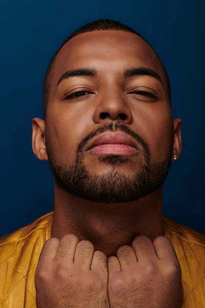 African american man with earring and beard looking at camera with hands on collar, fashion concept — Stock Photo
