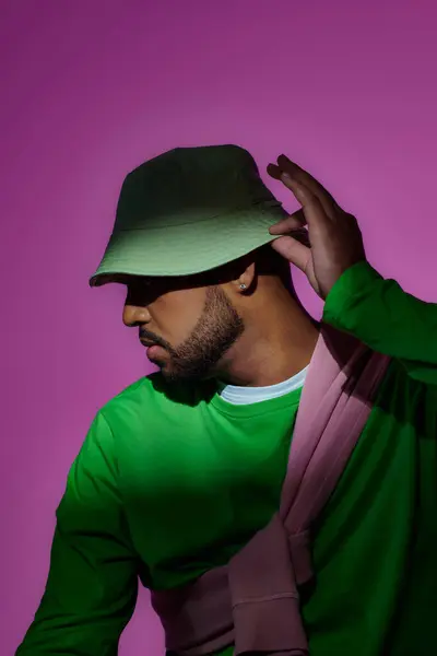Beau homme posant de profil avec boucle d'oreille et toucher son panama vert, concept de mode — Photo de stock