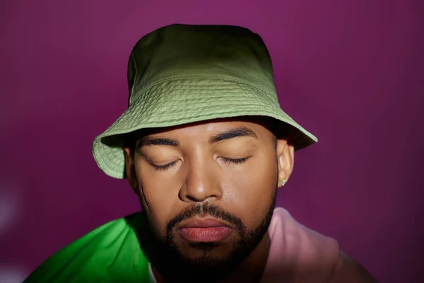 Close up young man in green panama with purple sweatshirt tied on shoulders, closed eyes, fashion — Stock Photo