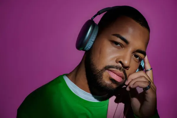 Homem americano africano bonito posando com fones de ouvido olhando para câmera, conceito de moda — Fotografia de Stock