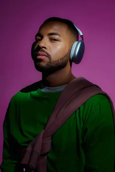 Good looking african american male model in green sweatshirt with headphones, fashion concept — Stock Photo
