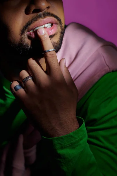 Vista recortada de un joven con tirantes y anillos tocándose el labio con el dedo, concepto de moda — Stock Photo