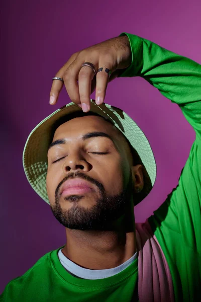 Gros plan jeune homme afro-américain en panama vert posant les yeux fermés, concept de mode — Photo de stock