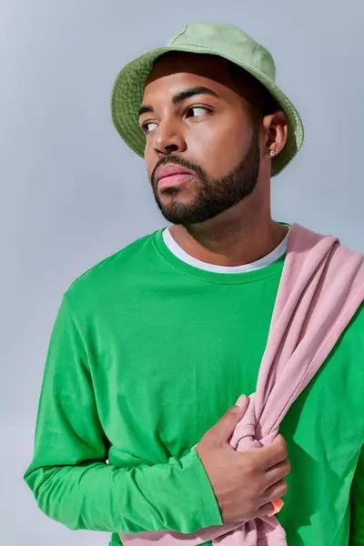 Retrato de hombre guapo en panama verde mirando hacia otro lado en el telón de fondo azul claro, concepto de moda - foto de stock