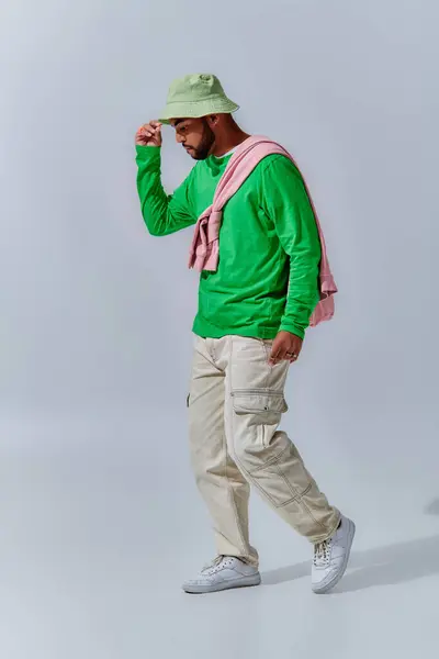 Beau jeune homme en streetwear branché posant de profil touchant son panama, concept de mode — Photo de stock