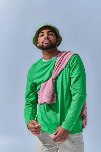 Stylish young man in green panama with pink sweatshirt tied on his shoulders, fashion concept — Stock Photo