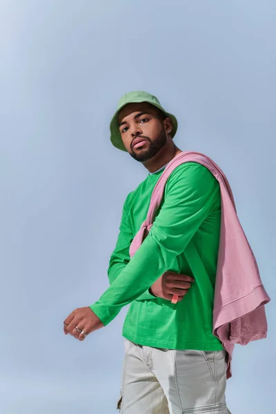 Handsome trendy man in green sweatshirt and panama posing actively on camera, fashion concept — Stock Photo