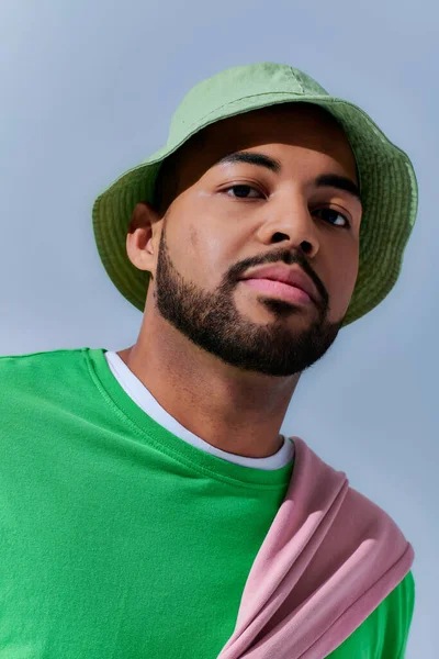 Retrato de joven hombre guapo con barba en panama verde mirando a la cámara, concepto de moda - foto de stock