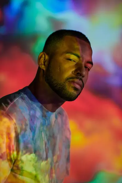 Portrait of handsome man looking at camera in colourful digital projector lights, fashion concept — Stock Photo