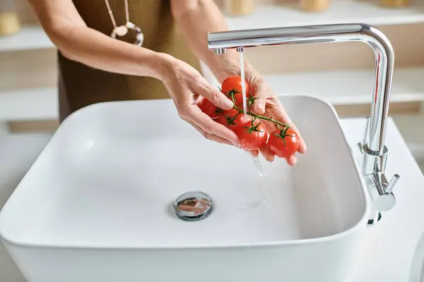 Обрізаний знімок жінки, що миє свіжі та стиглі вишневі помідори вдома, жіночі руки тримають овочі — стокове фото