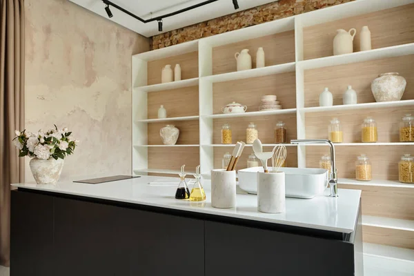 Elegante interior de la moderna cocina de lujo, flores en flor en jarrón, utensilios de cocina en la encimera - foto de stock