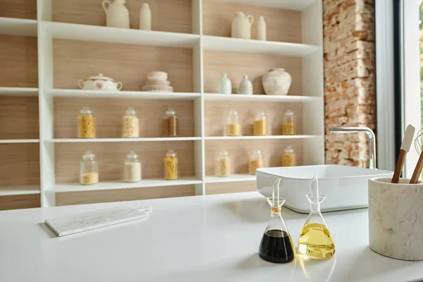 Interior elegante da cozinha moderna, garrafas de vidro com vinagre balsâmico e azeite na bancada — Fotografia de Stock