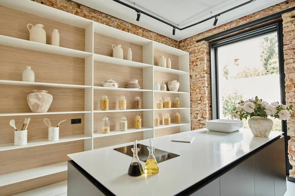 Elegante interno della cucina moderna, bottiglie di vetro vicino stufa elettrica sul piano di lavoro con fiori — Foto stock
