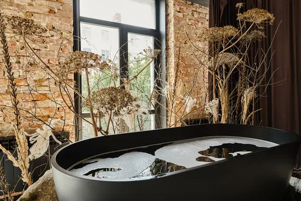 Acqua all'interno della vasca da bagno nera in appartamento moderno con finestre e piante decorative — Foto stock