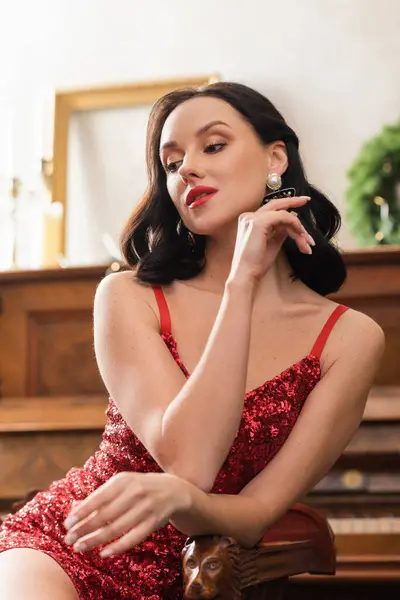 Retrato de mujer hermosa en vestido rojo sentado en silla vintage en apartamento de lujo, la vida rica - foto de stock