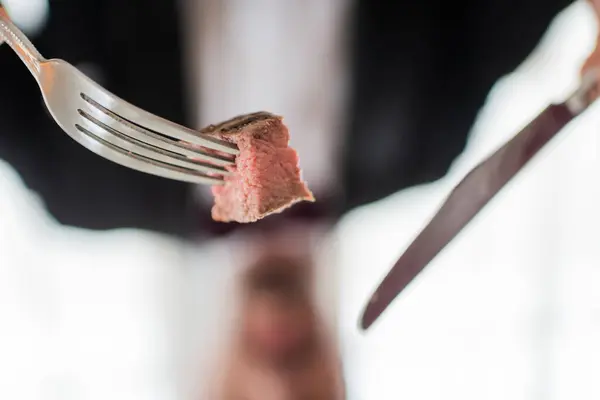 Крупным планом среднего приготовления вкусный стейк из говядины и серебряный нож и вилка, изысканная еда — стоковое фото