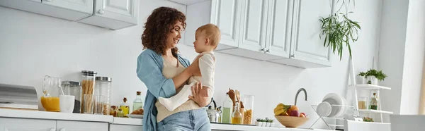 Donna gioiosa in piedi con adorabile figlia bambino nella moderna cucina spaziosa a casa, banner — Foto stock
