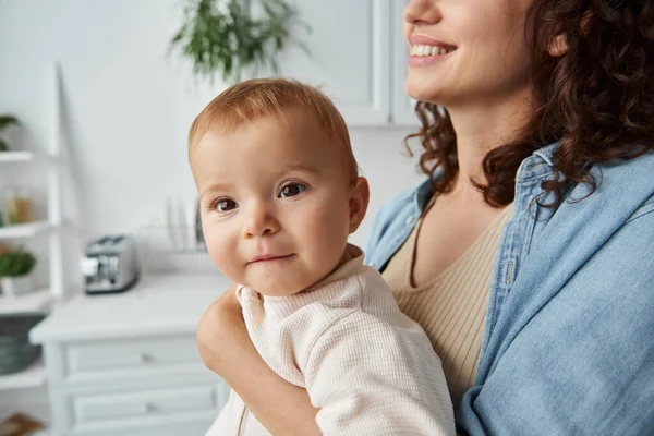 Ritratto di adorabile bambina in mano di madre sorridente in cucina a casa, infanzia beata — Foto stock