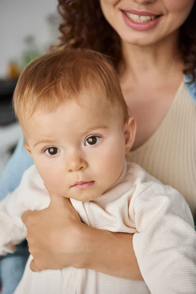 Retrato de niña en manos de madre cariñosa y sonriente en casa, infancia dichosa - foto de stock