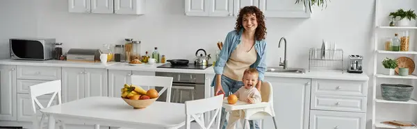 Aufgeregte Mutter und kleine Tochter blicken in die Kamera in der Nähe von frischem Obst in der modernen Küche, Banner — Stockfoto