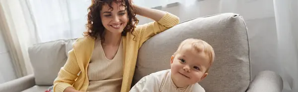 Sorrindo mulher olhando para adorável criança filha no sofá na sala de estar, tempo de qualidade, banner — Fotografia de Stock