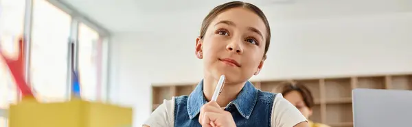 A young girl captivated, gazes upwards with wonder in lively classroom setting. — Stock Photo
