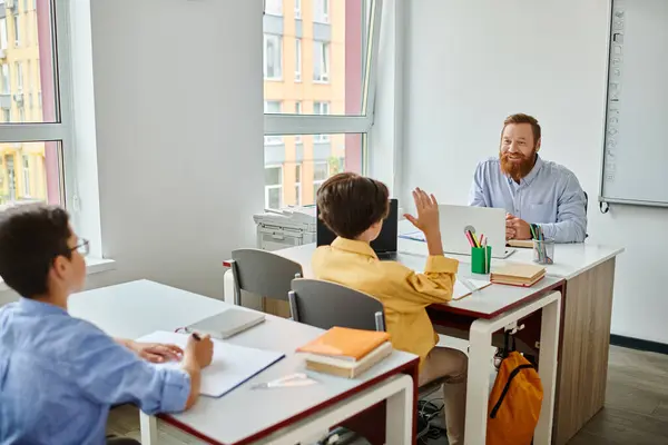 A group of students sit at desks facing a whiteboard, actively engaged in a lesson taught by a male teacher in a bright, lively classroom. — Stock Photo