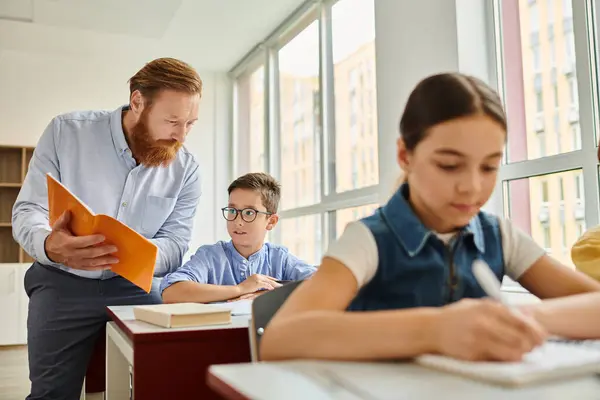 Un insegnante che istruisce un gruppo di bambini in un'aula luminosa e vivace. Un ragazzo ascolta attentamente mentre è seduto alle scrivanie. — Foto stock