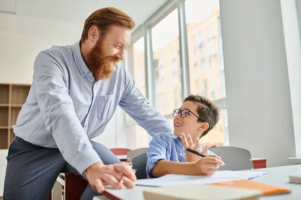 A teacher assists a young boy with his homework in a vibrant and engaging classroom setting — Stock Photo