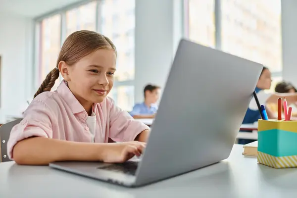 Una giovane ragazza si siede a un tavolo, concentrata sul suo computer portatile — Foto stock