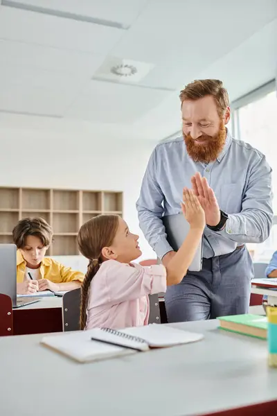 A man stands beside a little girl in a vibrant classroom, engaging in a learning activity with a group of kids. — Stock Photo