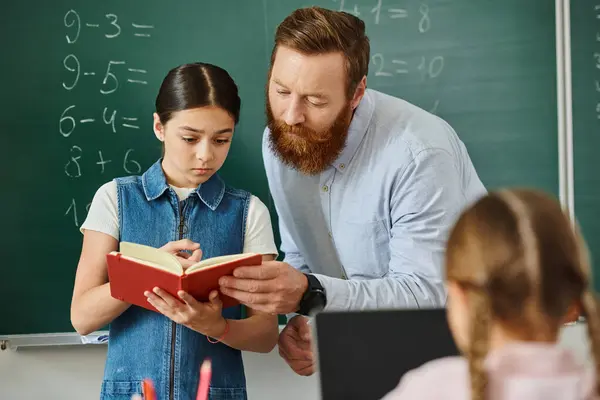 Un uomo si trova accanto a una bambina davanti a una lavagna, impegnato in una lezione in un ambiente di classe luminoso e vivace. — Foto stock