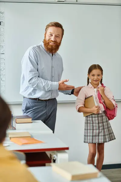 Un homme se tient à côté d'une petite fille dans une classe, s'engageant dans une activité éducative devant un tableau blanc. — Photo de stock