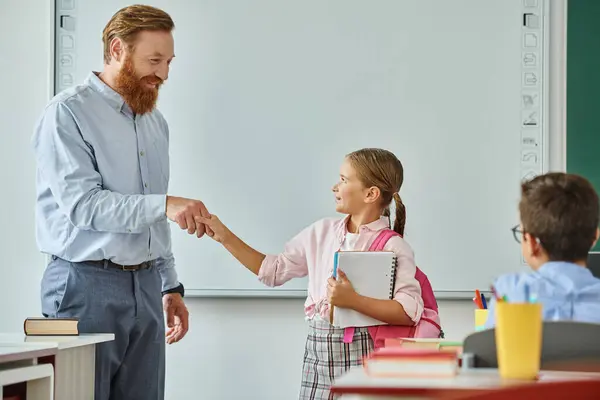 Учитель-мужчина в ярком классе пожимает руку молодой девушке, поддерживая связь и уважение между ними.. — стоковое фото
