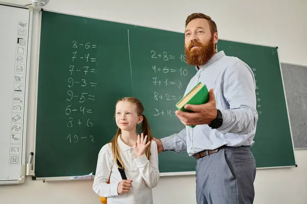 Un uomo in abiti casual sta accanto a una bambina, entrambi guardando con attenzione una lavagna piena di equazioni e diagrammi. — Foto stock
