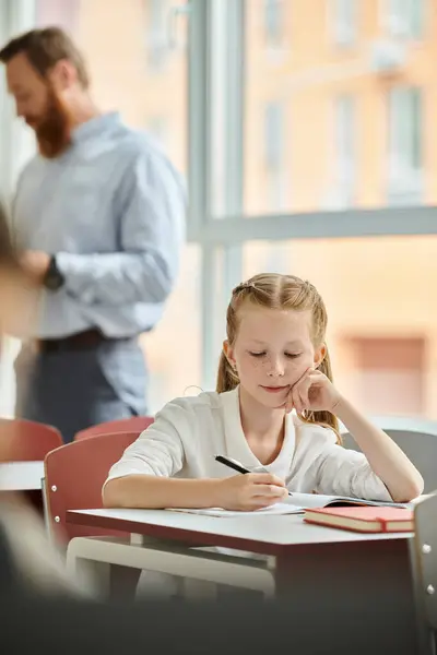 Une jeune fille brillante s'assoit à son bureau, s'engage dans l'apprentissage numérique. — Photo de stock