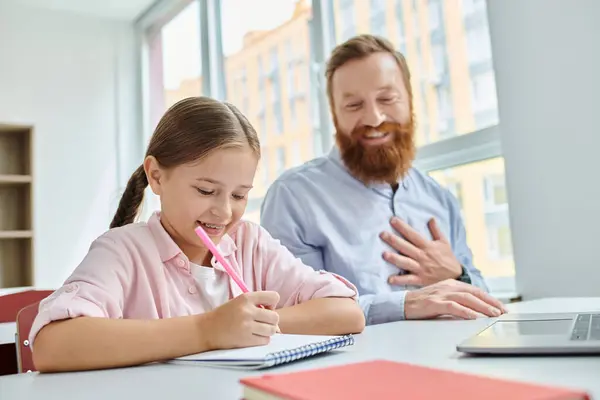 Um homem e uma menina se envolvem em uma lição animada em uma mesa colorida em um ambiente de sala de aula. — Fotografia de Stock